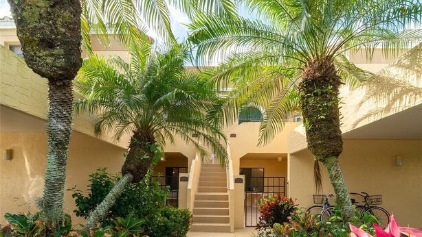 A courtyard with palm trees, a staircase, and a bike rack. - Renovated Beachwalk 3 Bedroom Condo -5 minute walk to Beach! (Naples)