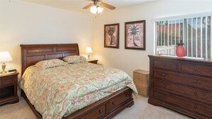 A bedroom with a large bed, wooden dresser, two bedside tables, and a ceiling fan. - Renovated Beachwalk 3 Bedroom Condo -5 minute walk to Beach! (Naples)