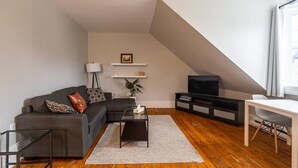 Una sala de estar moderna con un sofá, una mesa de centro, televisor y un comedor.