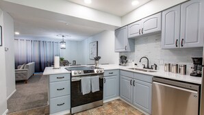 A modern kitchen with grey cabinets, stainless steel appliances, and a tiled backsplash. - Charming 4-bedroom Townhouse  25 min from Denver (Northglenn)