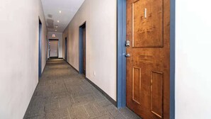 A hallway with a carpeted floor, wooden doors with blue trim, and recessed ceiling lighting. - Quaint Loft with AC, Abundance of Sunlight (Halifax)