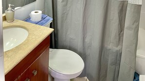 Une salle de bain comprenant des toilettes, un lavabo avec un distributeur de savon et un miroir.