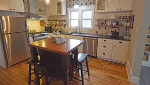 A kitchen with wooden flooring, white cabinets, stainless steel appliances, and pendant lighting. - 3BR Newly Renovated House in the heart of Sturgeon Bay (Sturgeon Bay)