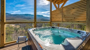 Un jacuzzi con terraza de madera y vistas a montañas.