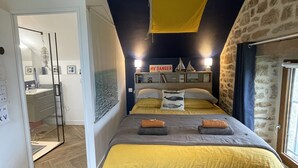 Une chambre à coucher avec un lit, un mur en pierre, une fenêtre et une porte.