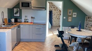 Une cuisine compacte dotée d’appareils électroménagers modernes, un coin repas avec un mur en pierre et une vue sur l’extérieur.