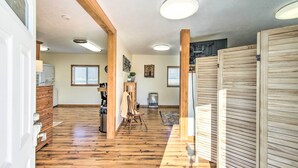 A spacious room with wooden flooring, a large window, and a wooden door.