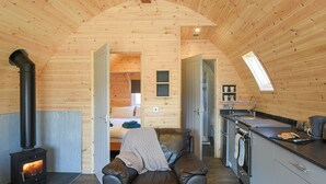 A cozy cabin interior with a fireplace, a sofa, a kitchen, and a loft bedroom. - Creyr Glas Pod -UK41796 (Penybontfawr, near Llanfyllin)