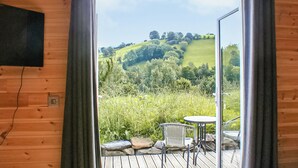 A wooden deck with a table and chairs, a glass door leading to a scenic hillside view. - Creyr Glas Pod -UK41796 (Penybontfawr, near Llanfyllin)