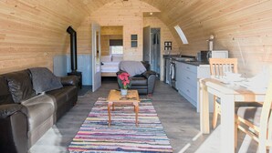 A cozy cabin interior with a wooden ceiling, a sofa, a coffee table, a kitchen area, and a bed. - Creyr Glas Pod -UK41796 (Penybontfawr, near Llanfyllin)