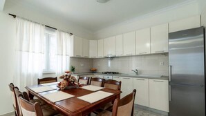 Una cucina moderna con mobili bianchi, un frigorifero in acciaio inossidabile e un tavolo con sedie.