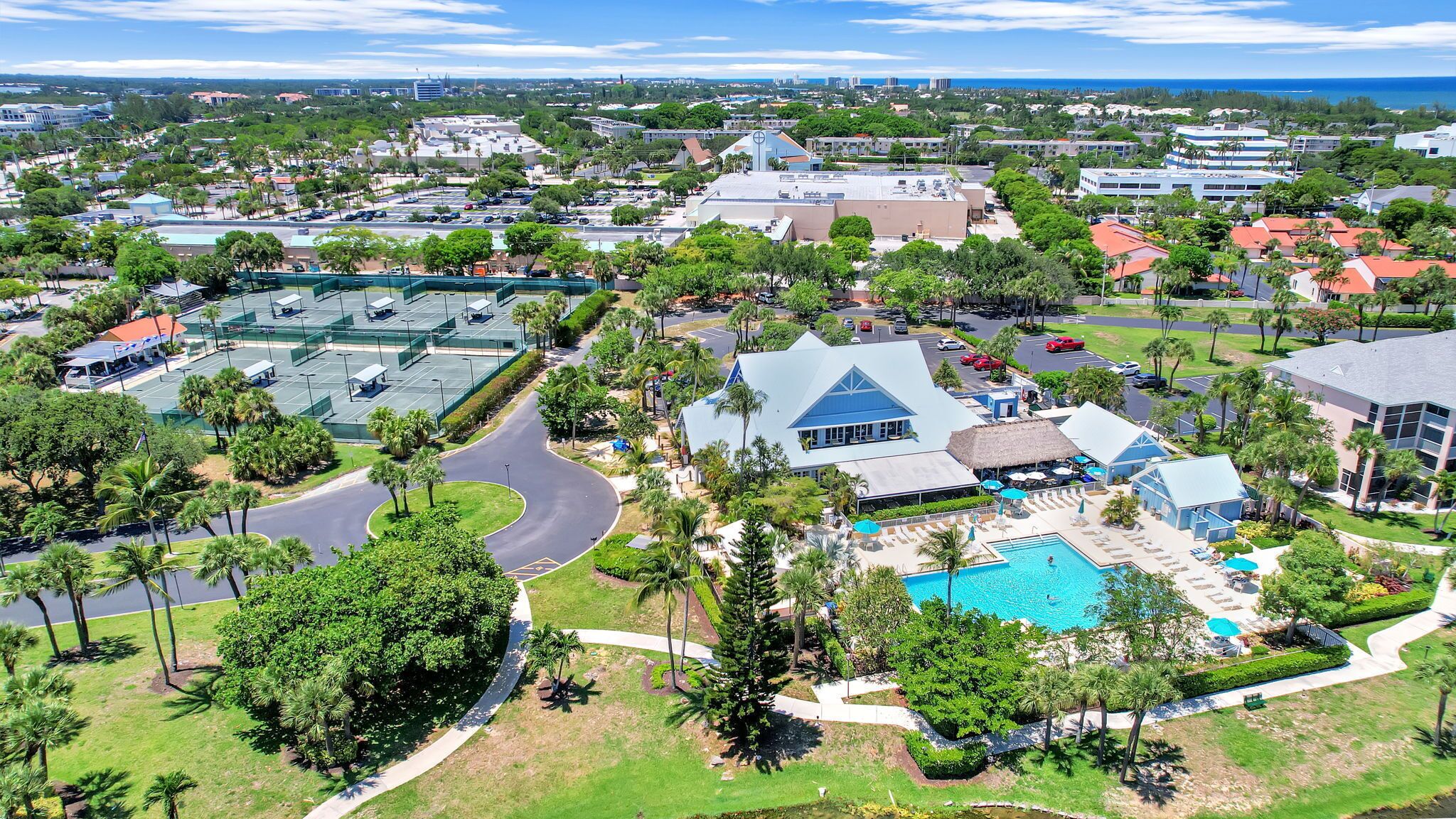 Un complejo turístico con una piscina grande, canchas de tenis y jardines exuberantes.