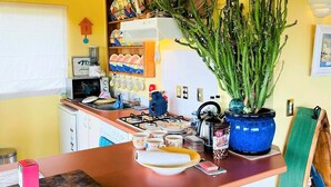A kitchen with a wooden ceiling, yellow walls, and a central island with a blue pot of plants.
