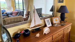 A room with a wooden dresser, a small sailboat model, a mirror, and a lamp.