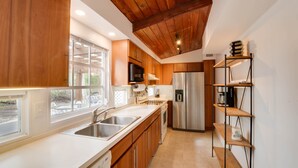 Una cucina moderna con mobili in legno, elettrodomestici in acciaio inossidabile e soffitto in legno.