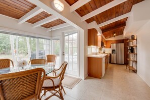 A modern kitchen with wooden beams, a dining area with wicker chairs, and a view of trees through large windows. - 9BR Estate | 3 Homes/2 Pools/Hot tub -30 Min to KW (Monroe County)