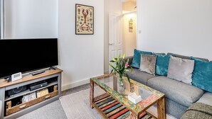 Un salon avec un canapé, une table basse, un téléviseur et une bibliothèque.