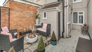 Une cour avec des meubles en osier, un foyer et des plantes en pot.