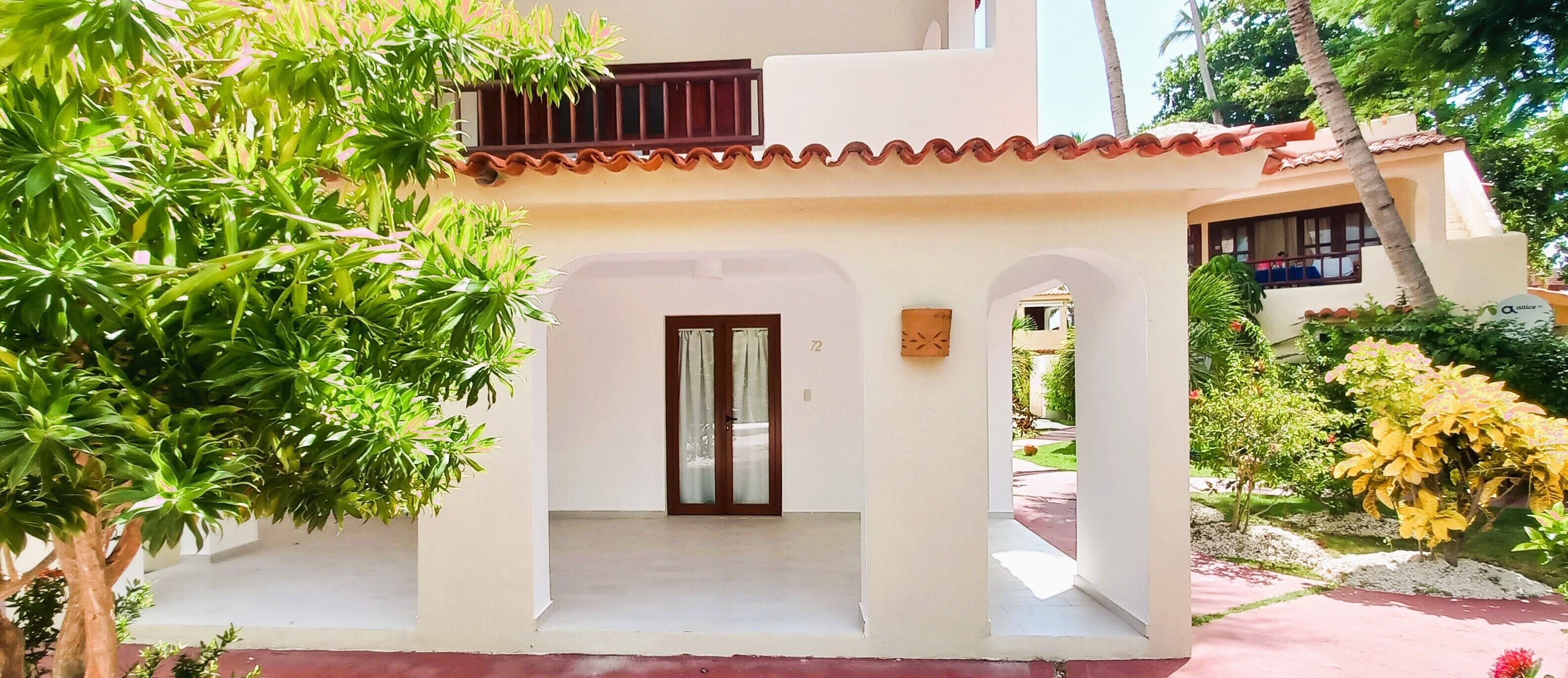 Ein Gebäude mit weißer Fassade, einem Ziegeldach und einem überdachten Eingang mit einer Tür.