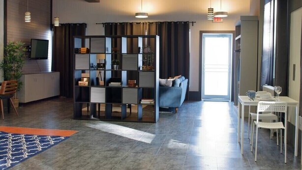 A modern hotel lobby with a seating area, a TV, and a bookshelf. - Suite with AC, Industrial Styling (Bedford)