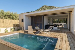 A modern outdoor pool area with a wooden deck, lounge chairs, and a dining area with outdoor furniture. - Villa ideal for family and friends - Private pool and spa - 5min beach (Monticello)