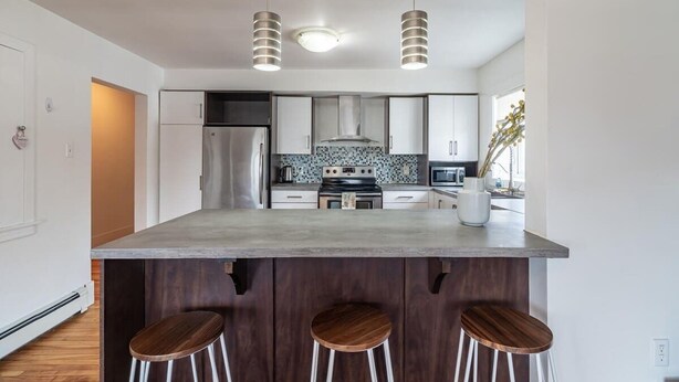 A modern kitchen with a central island, stainless steel appliances, and pendant lighting. - Beautiful & Spacious Apt, AC (Bedford)