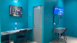 Ein tückisch-blaues Zimmer mit zwei Schreibtischen, Stühlen und einem Fernseher, der eine Speisekarte zeigt.