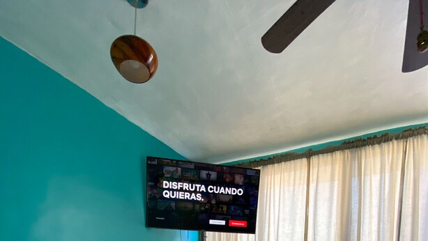 Ein Hotelzimmer mit Bett, Wandfernseher und einem Vorhangfenster.