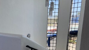 Eine Treppe mit Handlauf, ein Fenster mit Gitterstäben und ein Blick ins Freie.