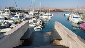 Un port de plaisance avec des bateaux amarrés, un ciel dégagé et un bâtiment en arrière-plan.