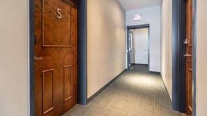 A hallway with a wooden door marked '5', carpeted floor, and a visible exit sign. - Family Friendly Downtown Loft with AC (Halifax)