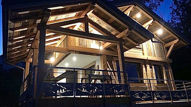 Een houten hut met balkon en groot raam.