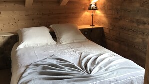 Een gezellig houten kamer met een bed, nachtkastje en lamp.