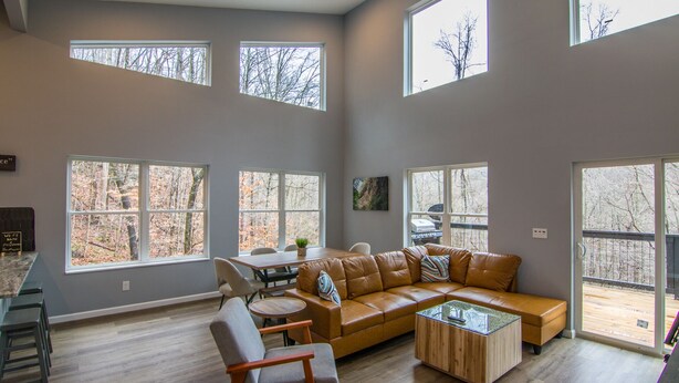 A spacious living room with large windows, a leather sofa, a coffee table, and a dining area. - Private RRG Retreat w/ Hot Tub & Game Room (Stanton)