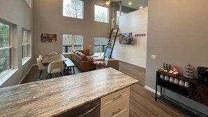 A spacious kitchen with a large island, a dining area with a sofa, and a staircase leading to an upper level. - Private RRG Retreat w/ Hot Tub & Game Room (Stanton)
