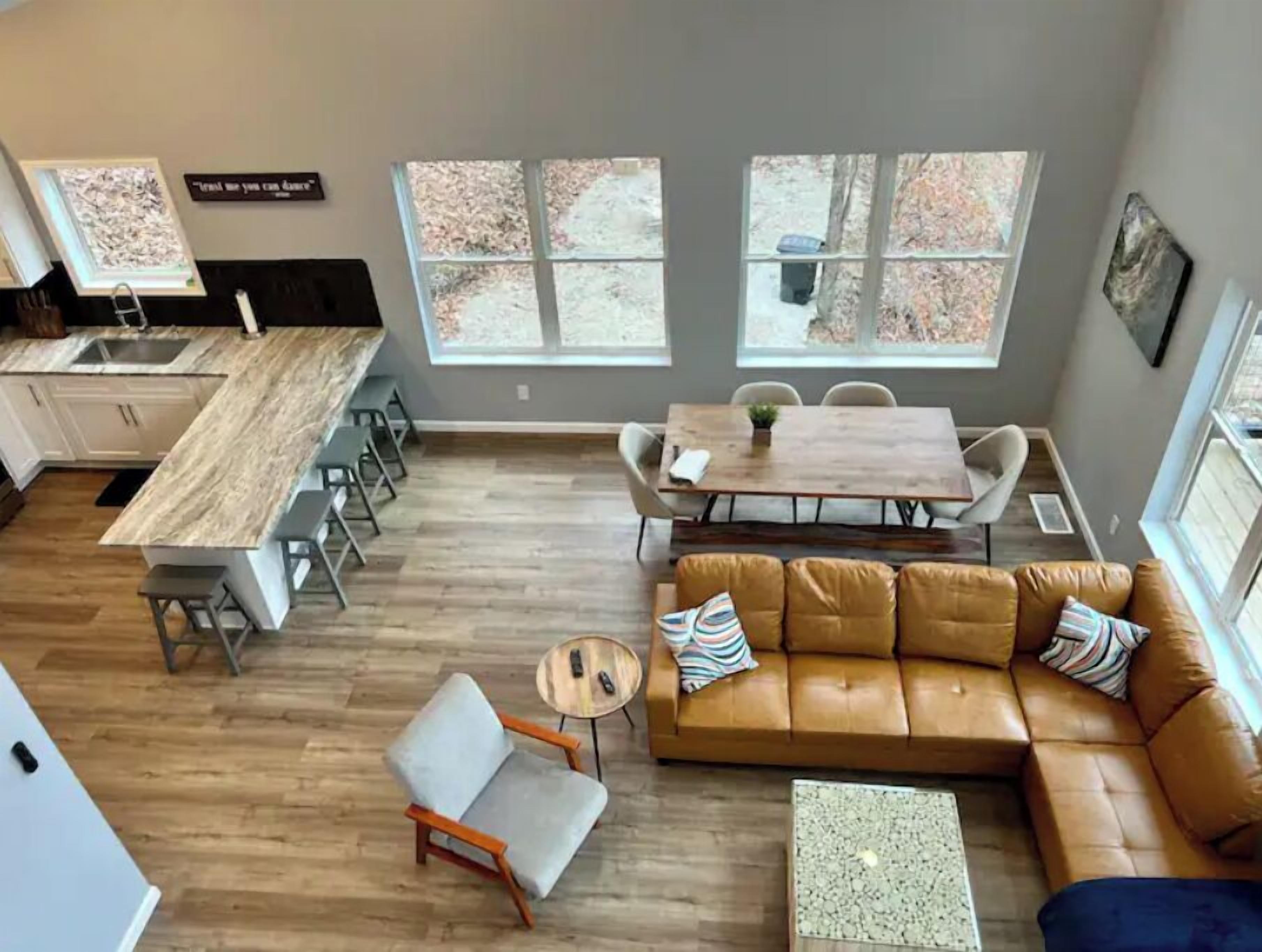 A spacious living area with a large brown leather sofa, a dining table, and a kitchen with a marble countertop.