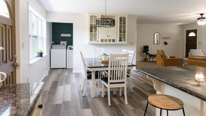 A modern kitchen with white cabinetry, a dining table with chairs, a built-in oven, and a ceiling fan. - Cozy and secluded getaway with hot tub & fireplace (Halifax)