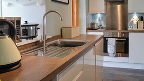 Een moderne keuken met roestvrijstalen apparatuur, een houten aanrechtblad en een inbouwoven.