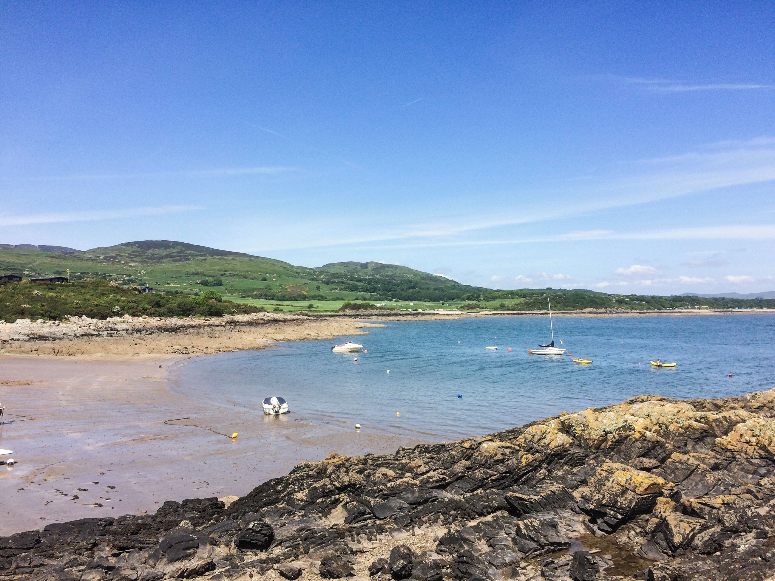 A coastal landscape with rocky shores, calm water, and boats.