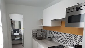 Moderni keittiö, jossa on valkoiset kaapit, ruostumattomasta teräksestä valmistettu pesuallas ja mikroaaltouuni.