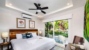 A bedroom with a large bed, a ceiling fan, an air conditioning unit, and a view of a garden through a sliding glass door. - Surfer`s Heaven - Modern, new home, close to beach (Playa Avellanas)