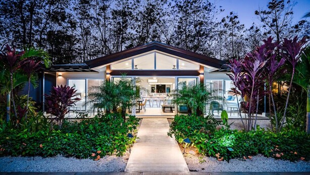 A modern house with a covered patio, surrounded by lush greenery and a well-maintained garden. - Surfer`s Heaven - Modern, new home, close to beach (Playa Avellanas)