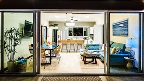 A modern living room with a dining area, a kitchen in the background, and a large sliding glass door leading to an outdoor space. - Surfer`s Heaven - Modern, new home, close to beach (Playa Avellanas)