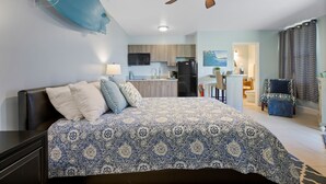Un dormitorio con cama, ventilador de techo y vista a la cocina.