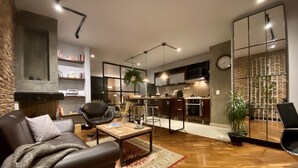 Ein modernes Wohnzimmer mit Sofa, Couchtisch und einem Essbereich mit Stühlen sowie einer Küche im Hintergrund.