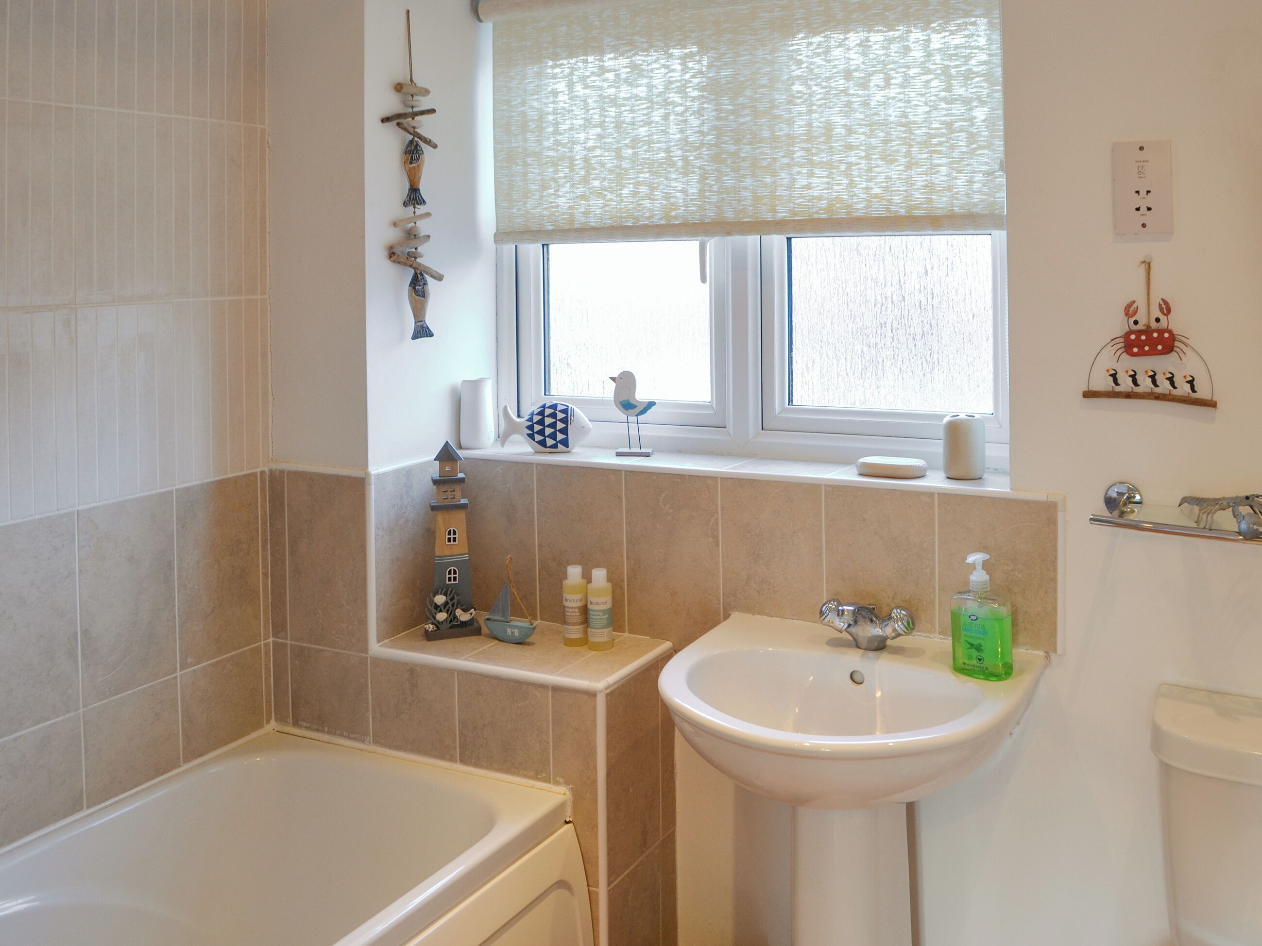 A bathroom with a bathtub, sink, and window.