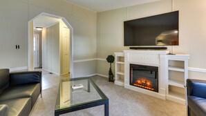 Una sala de estar con chimenea, televisor y dos sofás de cuero.