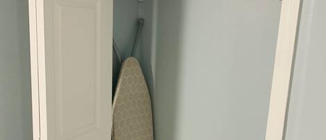 A closet with a hanging rack for towels and a storage shelf.