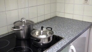 A kitchen with a stove, two pots, and a white tiled backsplash. - 1 Studio Flat walking distance to ski lifts (we have 2 in the same building) (Kaprun)
