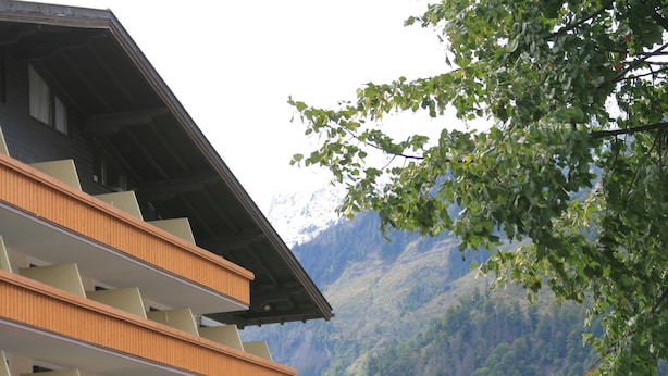 A multi-story building with balconies, a mountain backdrop, and solar panels on the roof. - 1 Studio Flat walking distance to ski lifts (we have 2 in the same building) (Kaprun)